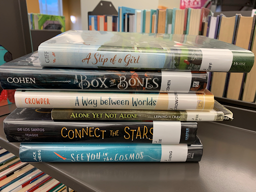 Book spines say: A slip of a girl, a box of bones, a way between worlds, alone yet not alone, connect the stars, see you in the cosmos